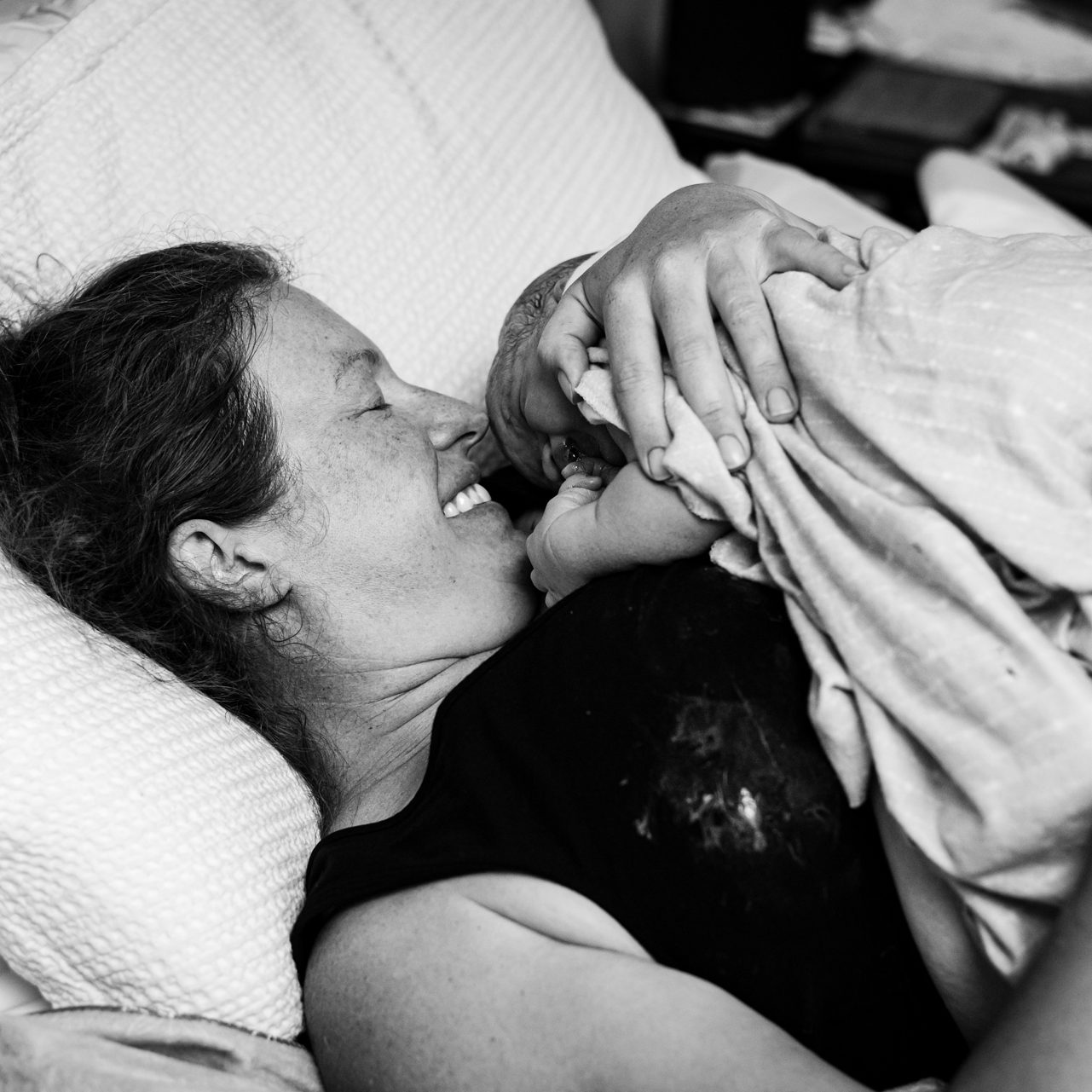 mom smiling at newborn baby